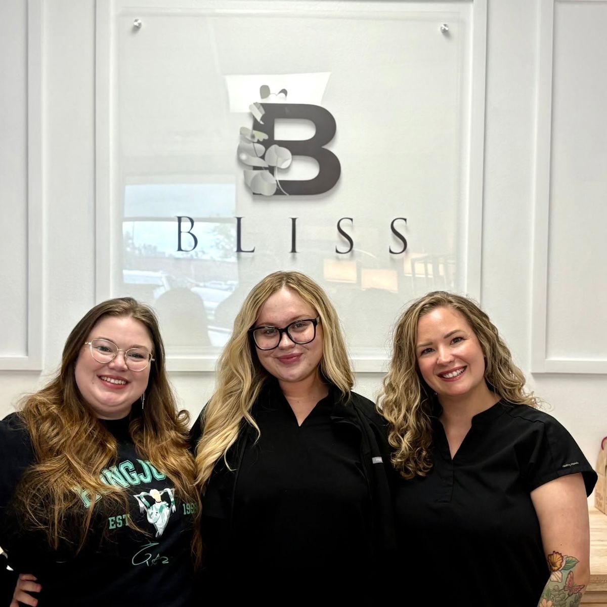 The Bliss Health Spa team in front of the Bliss logo wall